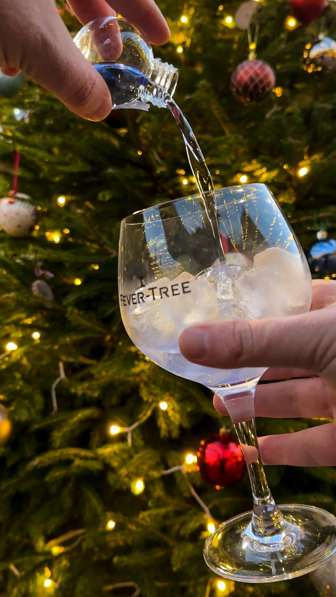 pouring torbay gin bauble into fever tree gin and tonic glass by cockington christmas tree